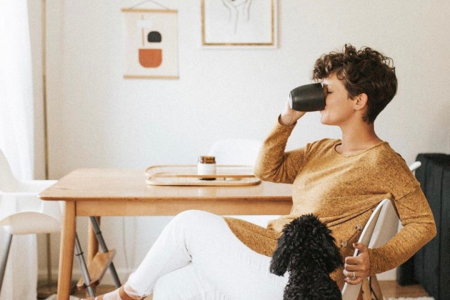 "person drinking morning cup of coffee at table with candle"